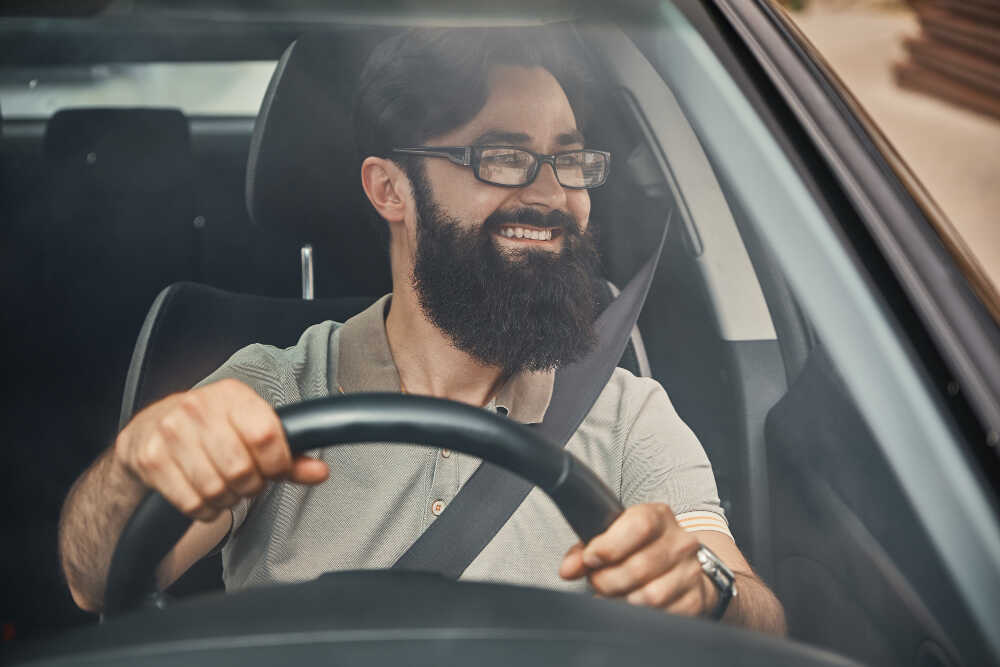 young man looking around while driving a car in a residential area